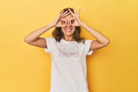 Photo for Portrait of adult woman showing okay sign over eyes - Royalty Free Image