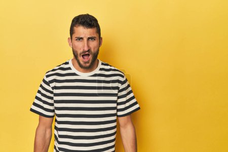 Photo for Young Hispanic man on yellow background shouting very angry, rage concept, frustrated. - Royalty Free Image