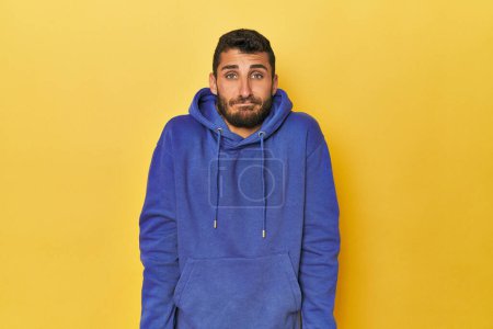 Photo for Young Hispanic man on yellow background shrugs shoulders and open eyes confused. - Royalty Free Image