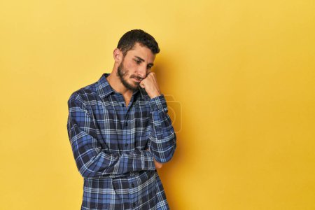 Téléchargez les photos : Jeune homme hispanique sur fond jaune qui se sent triste et coûteux, en regardant l'espace de copie. - en image libre de droit