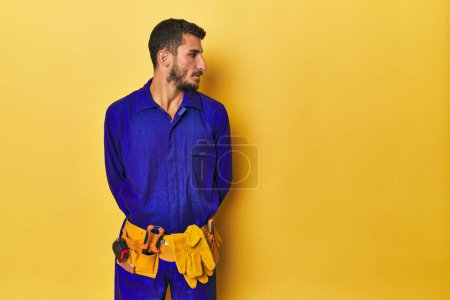 Photo for Hispanic young man in blue work jumpsuit with tools - Royalty Free Image