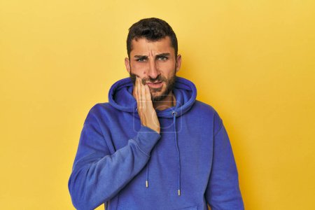 Photo for Young Hispanic man on yellow background having a strong teeth pain, molar ache. - Royalty Free Image
