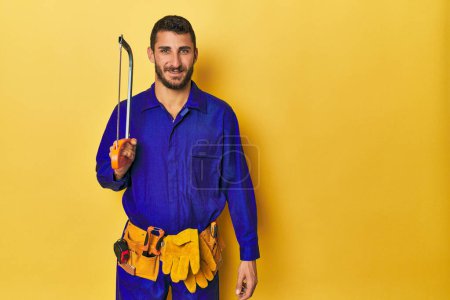 Photo for Young Hispanic man with saw and tool belt poses - Royalty Free Image