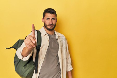 Photo for Young Hispanic man with travel backpack showing number one with finger. - Royalty Free Image