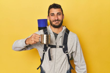 Téléchargez les photos : Jeune homme hispanique avec tasse et sac de camping - en image libre de droit