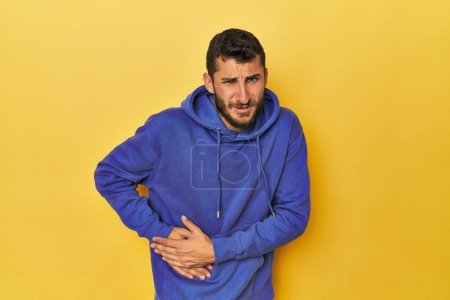 Photo for Young Hispanic man on yellow background having a liver pain, stomach ache. - Royalty Free Image