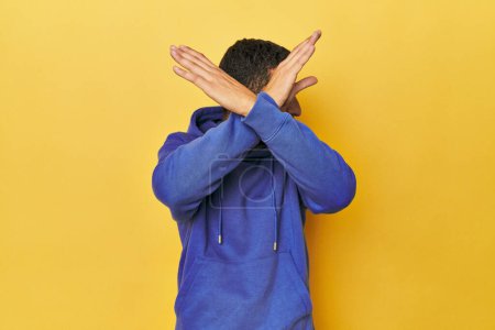 Photo for Young Hispanic man on yellow background keeping two arms crossed, denial concept. - Royalty Free Image