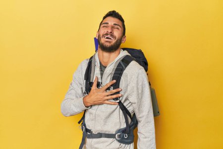 Photo for Young Hispanic man ready for hiking laughs out loudly keeping hand on chest. - Royalty Free Image