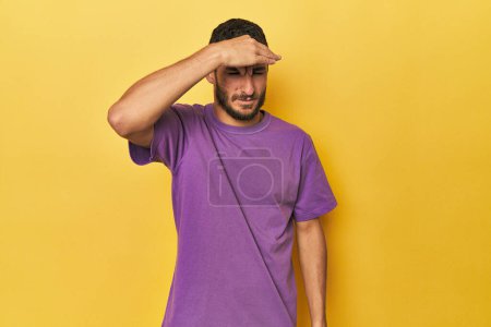Photo for Young Hispanic man on yellow background having a head ache, touching front of the face. - Royalty Free Image