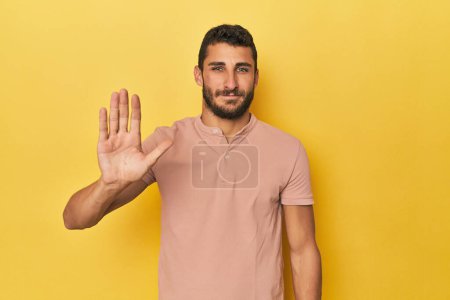 Photo for Young Hispanic man on yellow background smiling cheerful showing number five with fingers. - Royalty Free Image