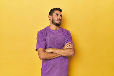 Photo for Young Hispanic man on yellow background tired of a repetitive task. - Royalty Free Image