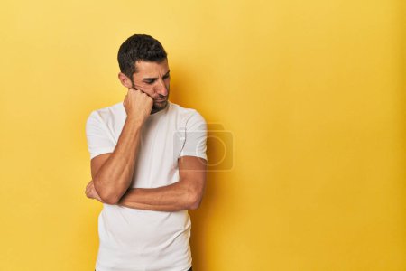 Téléchargez les photos : Jeune homme hispanique sur fond jaune qui se sent triste et coûteux, en regardant l'espace de copie. - en image libre de droit