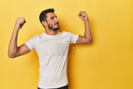 Photo for Young Hispanic man on yellow background raising fist after a victory, winner concept. - Royalty Free Image