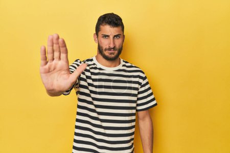 Téléchargez les photos : Jeune homme hispanique sur fond jaune debout avec la main tendue montrant le signe d'arrêt, vous empêchant. - en image libre de droit