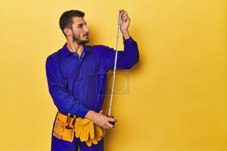 Photo for Young Hispanic man using a measuring tape - Royalty Free Image
