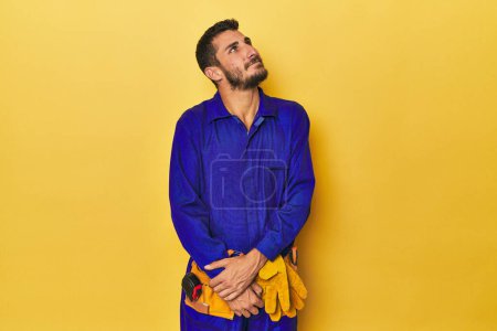 Photo for Young Hispanic man in a blue jumpsuit Young Hispanic man in a blue jumpsuitdreaming of achieving goals and purposes - Royalty Free Image