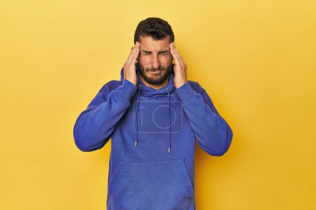 Photo for Young Hispanic man on yellow background touching temples and having headache. - Royalty Free Image