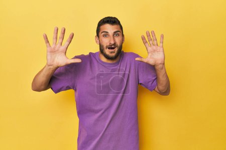 Téléchargez les photos : Jeune homme hispanique sur fond jaune recevant une agréable surprise, excité et levant la main. - en image libre de droit