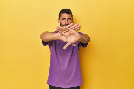 Photo for Young Hispanic man on yellow background doing a denial gesture - Royalty Free Image
