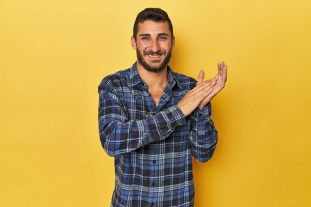 Téléchargez les photos : Jeune homme hispanique sur fond jaune se sentant énergique et confortable, les mains frottées confiantes. - en image libre de droit