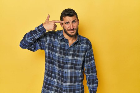 Téléchargez les photos : Jeune homme hispanique sur fond jaune montrant un geste de déception avec index. - en image libre de droit