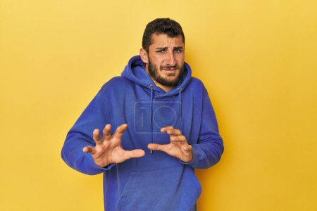 Photo for Young Hispanic man on yellow background rejecting someone showing a gesture of disgust. - Royalty Free Image