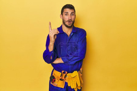 Photo for Young Hispanic man in a blue jumpsuit Young Hispanic man in a blue jumpsuithaving some great idea, concept of creativity. - Royalty Free Image