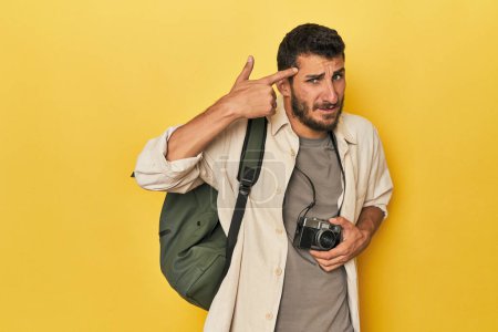 Photo for Young Hispanic travel photographer poses showing a disappointment gesture with forefinger. - Royalty Free Image