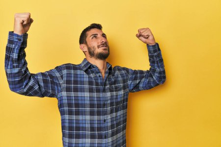 Photo for Young Hispanic man on yellow background raising fist after a victory, winner concept. - Royalty Free Image