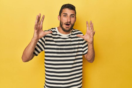 Photo for Young Hispanic man on yellow background screaming to the sky, looking up, frustrated. - Royalty Free Image