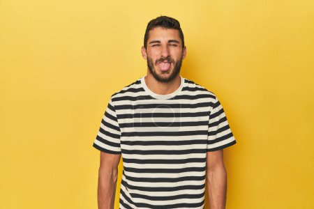 Photo for Young Hispanic man on yellow background funny and friendly sticking out tongue. - Royalty Free Image