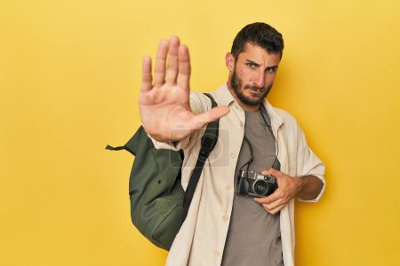 Téléchargez les photos : Jeune photographe de voyage hispanique pose debout avec la main tendue montrant le signe d'arrêt, vous empêchant. - en image libre de droit