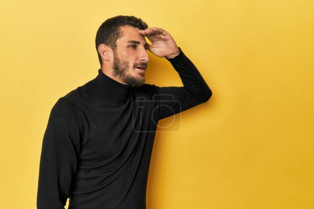 Téléchargez les photos : Jeune homme hispanique sur fond jaune regardant loin en gardant la main sur le front. - en image libre de droit