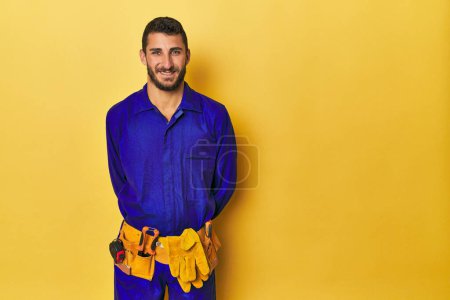 Photo for Hispanic young man in blue work jumpsuit with tools - Royalty Free Image