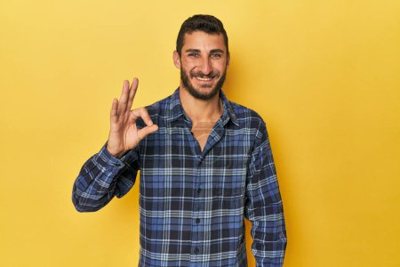 Photo for Young Hispanic man on yellow background cheerful and confident showing ok gesture. - Royalty Free Image