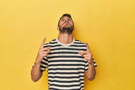 Photo for Young Hispanic man on yellow background pointing upside with opened mouth. - Royalty Free Image