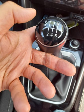 A MAN'S HAND ON THE GEAR LEVER OF THE CAR
