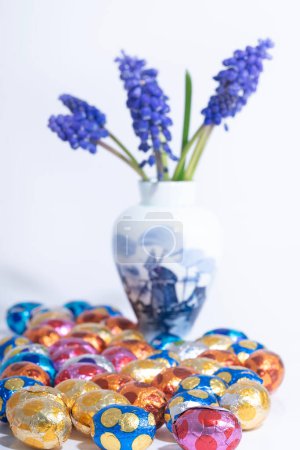 Eine Delfts blaue Vase hält eine blaue Traubenhyazinthenblüte neben Ostereiern, wodurch eine kreative Kunstausstellung entsteht, die sich perfekt für jedes Ereignis oder Modeaccessoire eignet