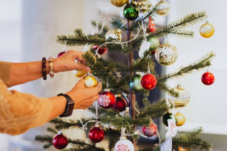 Téléchargez les photos : Senior homme décorer un arbre de Noël à la maison - en image libre de droit
