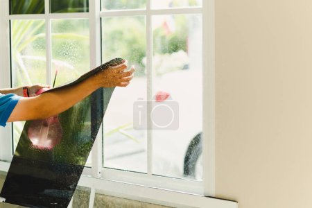 Photo for Woker wrapping tinting filma on house window using foggy spray. - Royalty Free Image