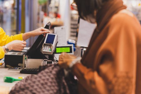 Cliente mujer pagando con tarjeta de crédito usando tecnología NFC en centro comercial