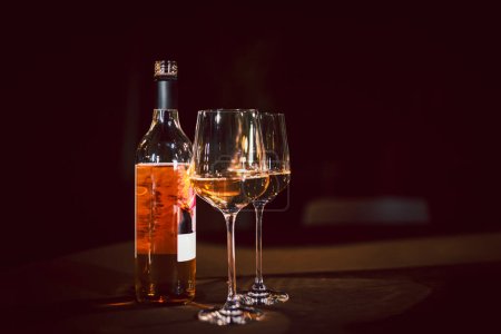 Foto de Vasos y botella de vino rosa en la mesa de la cena - Imagen libre de derechos