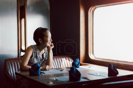 Téléchargez les photos : Heureuse femme souriante assise seule au restaurant regardant ailleurs - en image libre de droit