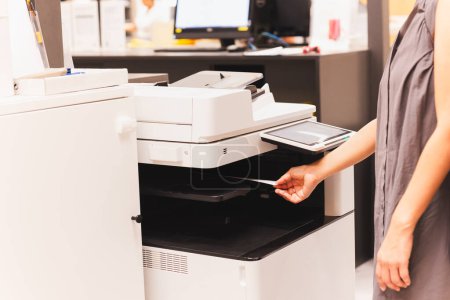 Téléchargez les photos : Les femmes tirent à la main le document papier d'impression de l'imprimante de bureau fonctionnelle - en image libre de droit