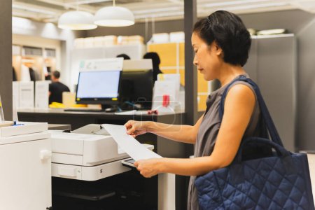 Téléchargez les photos : Empreintes de femme d'affaires sur l'imprimante dans le bureau - en image libre de droit