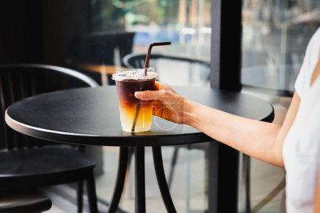 Téléchargez les photos : Femme buvant du café glacé dans une tasse en plastique à emporter au café extérieur de table - en image libre de droit