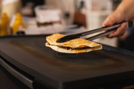Téléchargez les photos : Chef préparant quesadilla frais sur grill noir au marché alimentaire local - en image libre de droit