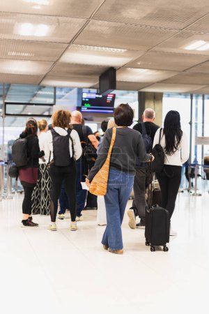 Téléchargez les photos : Femme avec bagages debout dans une file d'attente à l'aéroport - en image libre de droit