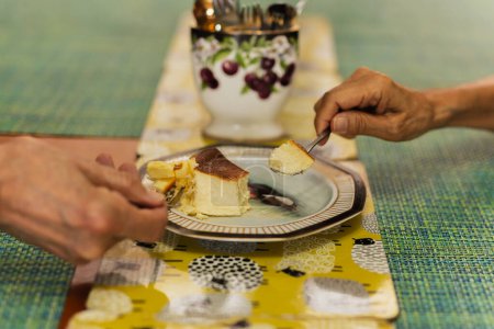 Téléchargez les photos : Senior couple mains avec cuillère manger cheesecake brûlé - en image libre de droit