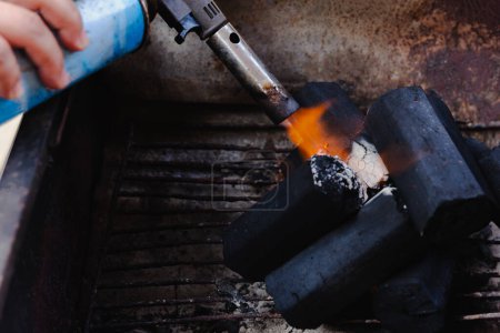Hombre usando la antorcha del encendedor de barbacoa para iniciar el fuego para carbón